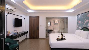 Una habitación de hotel moderna con cama, escritorio, silla, televisión y zona de ducha.
