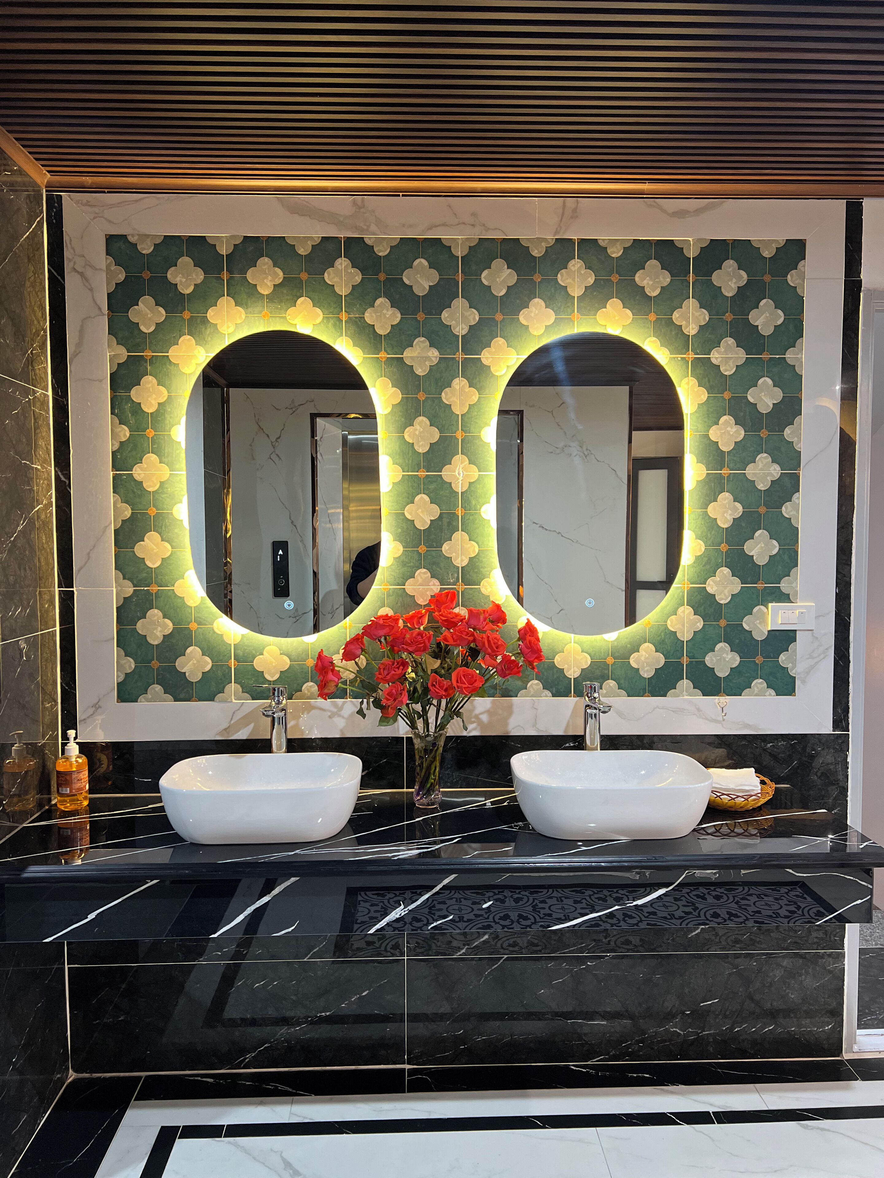 Un bagno con due lavandini, uno specchio e una parete con motivi floreali.