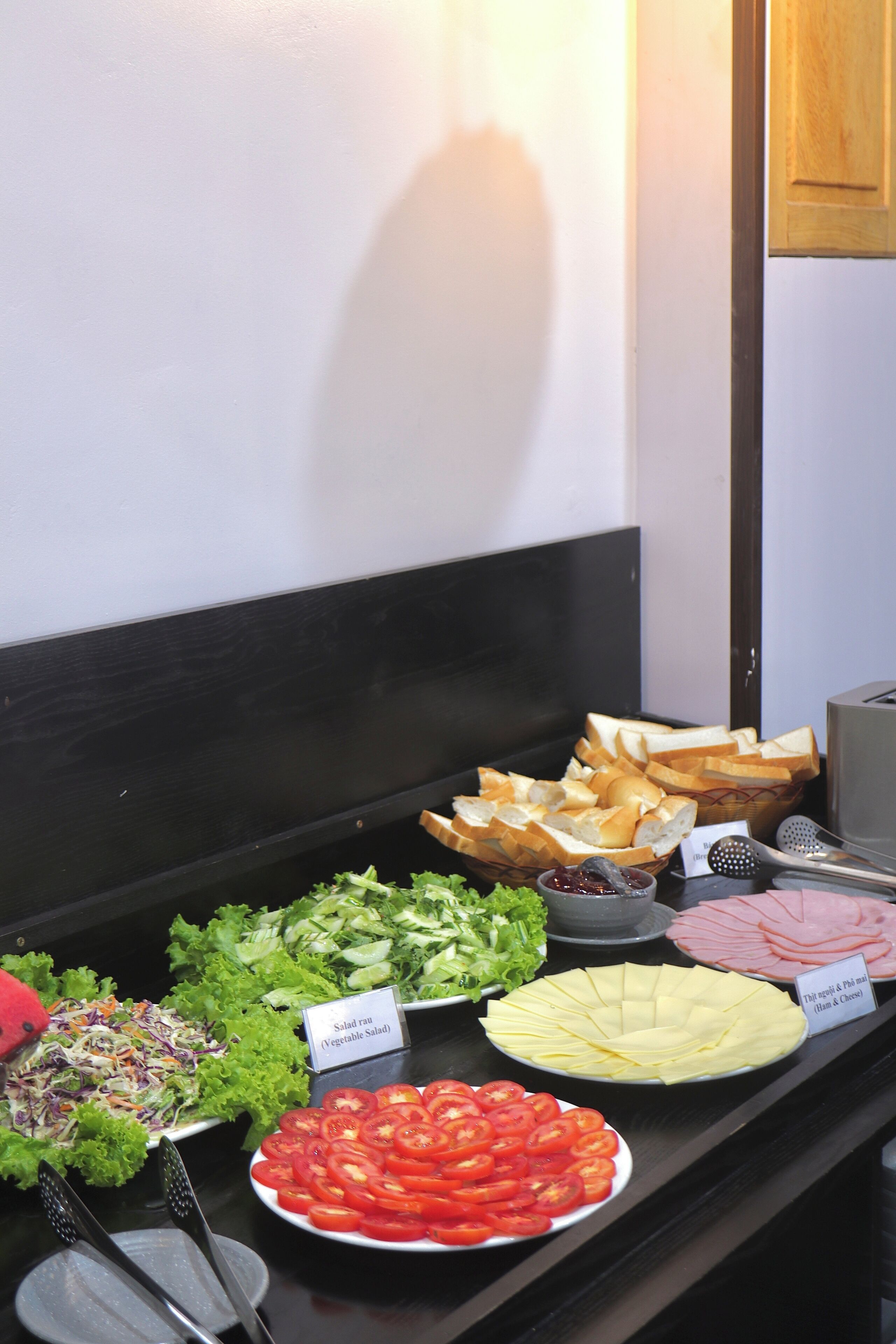 A buffet with various food options including salads, bread, and sliced meats.