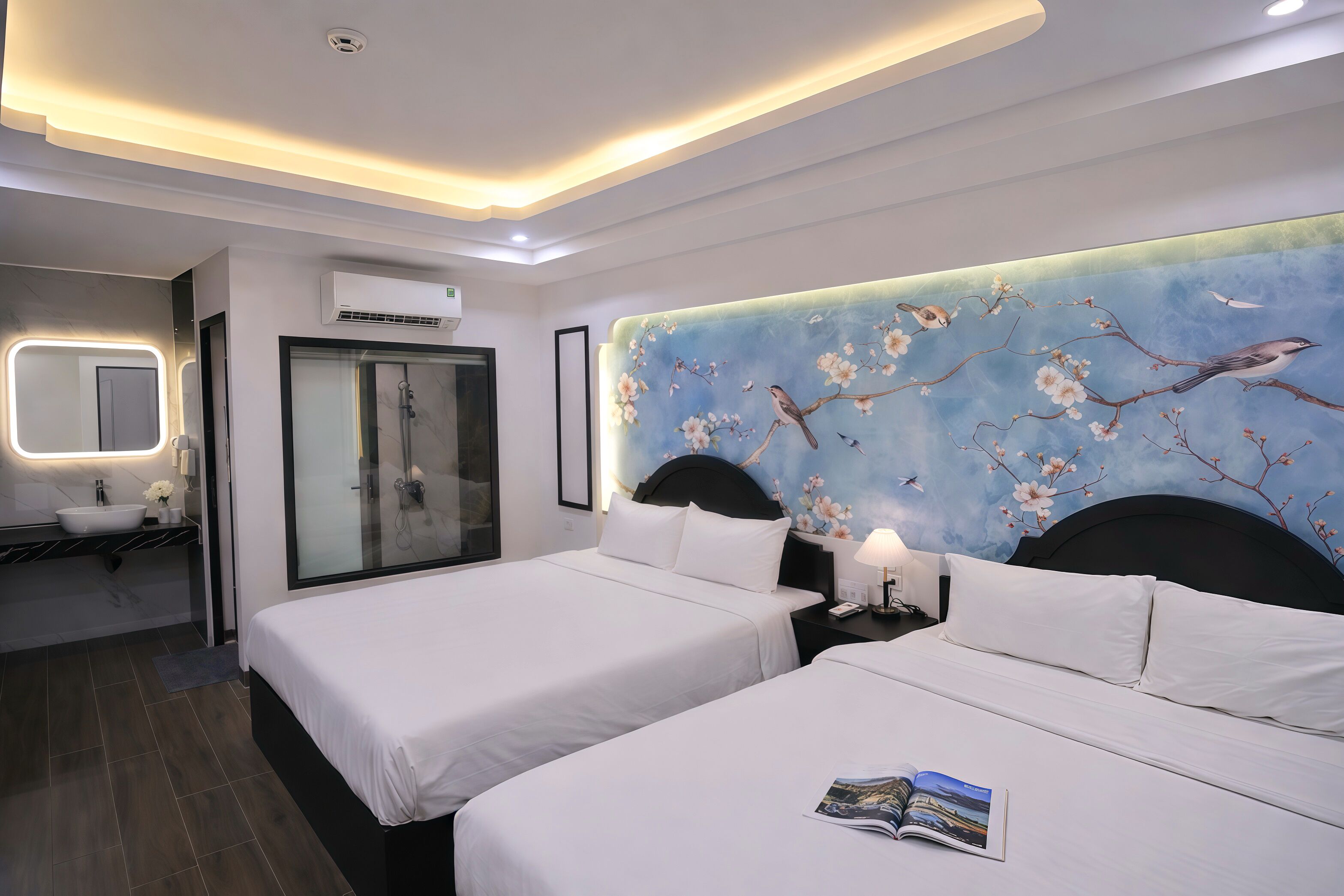 A hotel room with two beds, a large mirror, a vanity with a sink, and a shower.