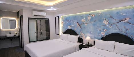 A hotel room with two beds, a large mirror, a vanity with a sink, and a shower.