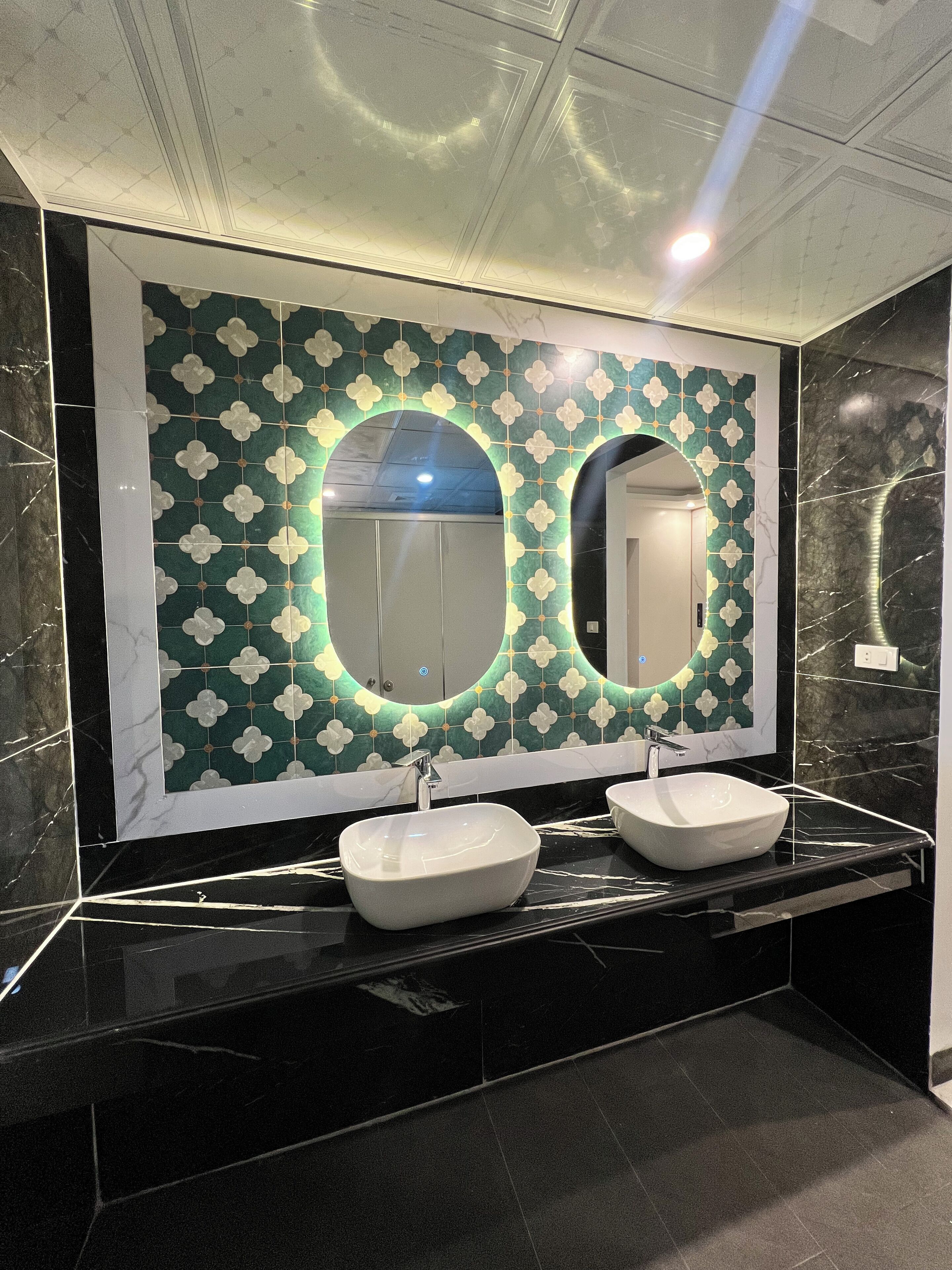 Un baño con dos lavamanos, un espejo grande y una pared decorada con azulejos.
