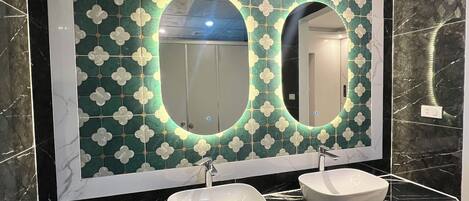 Un baño con dos lavamanos, un espejo grande y una pared decorada con azulejos.