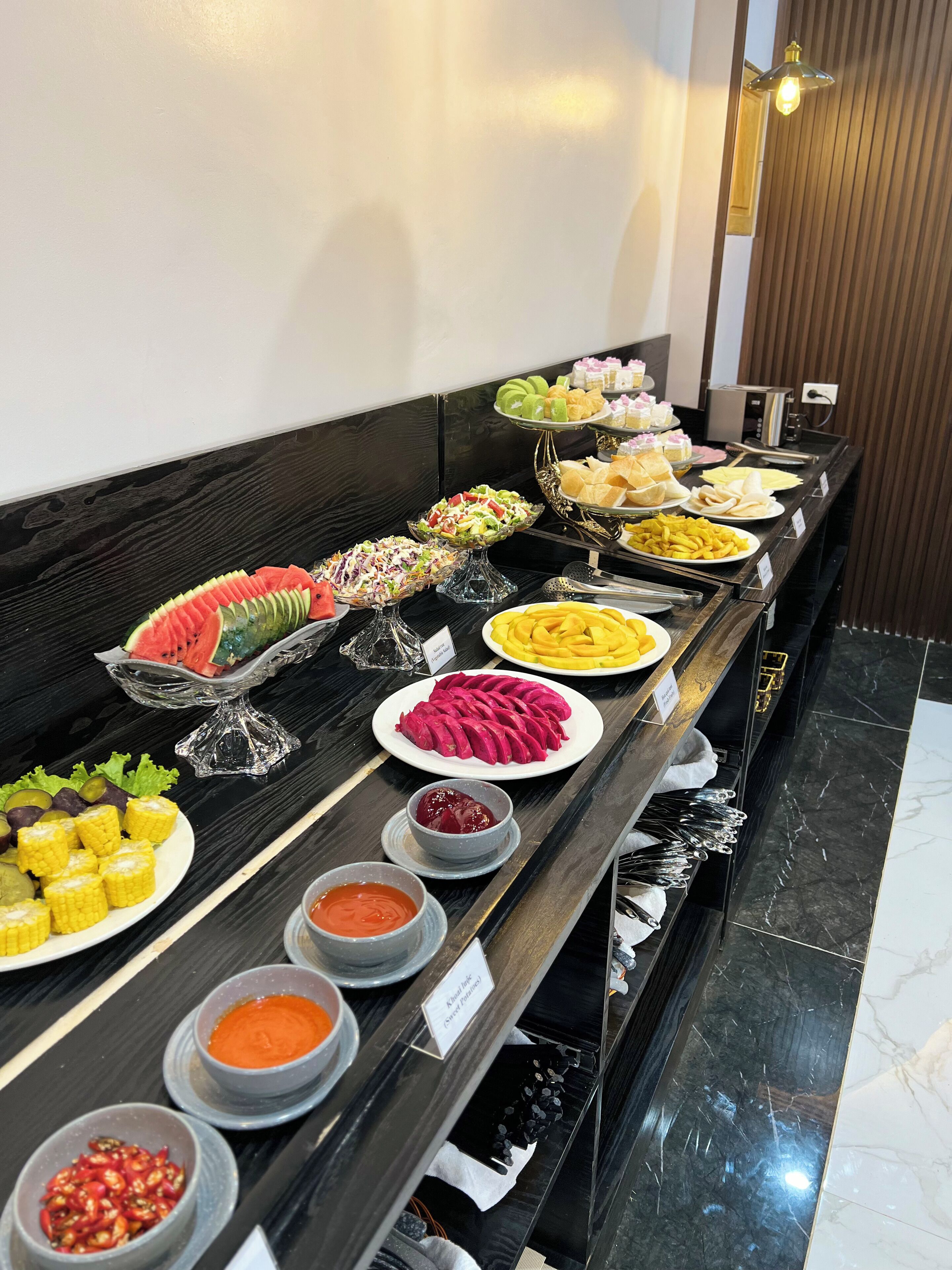 A buffet table with various food items and condiments.