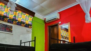Una habitación con dos camas, un muro colorido y un ventilador de techo.