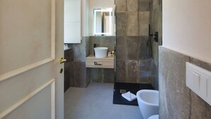 Een moderne badkamer met een witte wastafel, een douche met glazen wanden en een toilet.