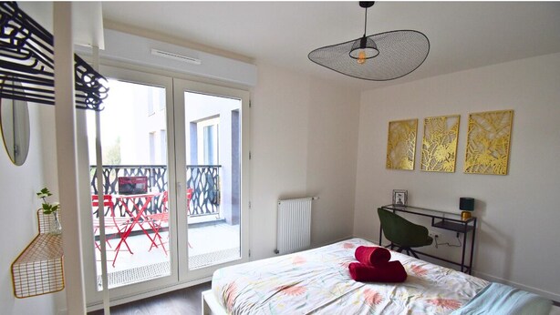 Une chambre à coucher comprenant un lit, un bureau, une chaise et un balcon avec une table et des chaises.