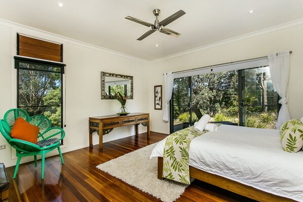 A bedroom with a bed, a chair, a desk, and a large window.