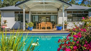 Uma casa com alpendre, piscina e plantas em vasos.