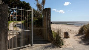 A gated entrance to a beach area with a clear view of the sea and a distant shoreline. - Rose-May by Interhome (La Bernerie-en Retz)