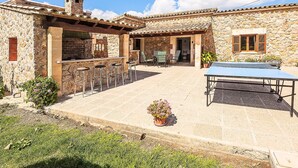 Un edificio de piedra con patio, mesas al aire libre y una mesa de ping pong.