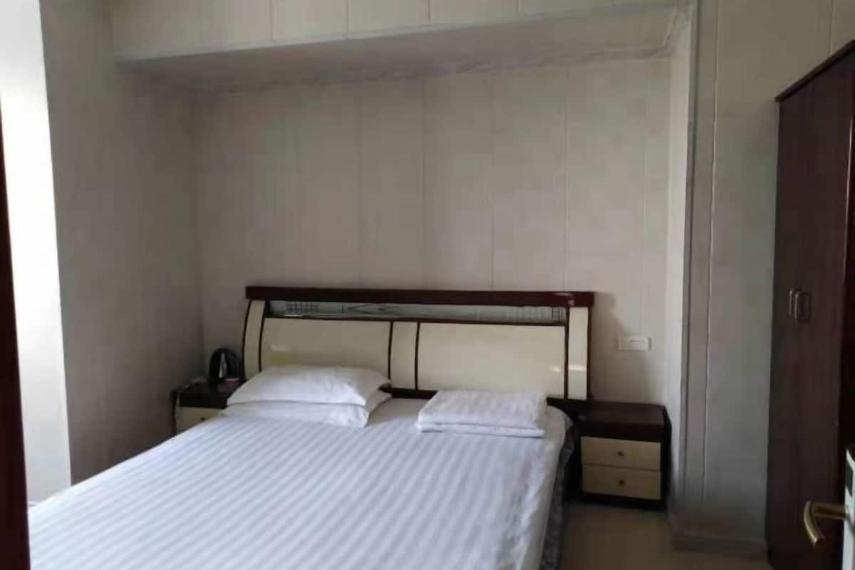 A single bed with a wooden headboard, a nightstand with a lamp, and a wardrobe.