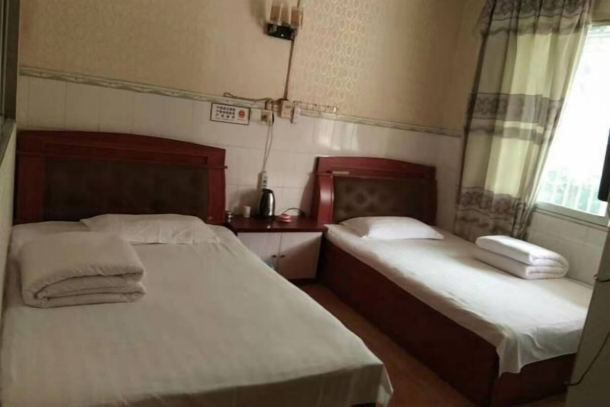 A hotel room with two beds, a bedside table, and a window with curtains.