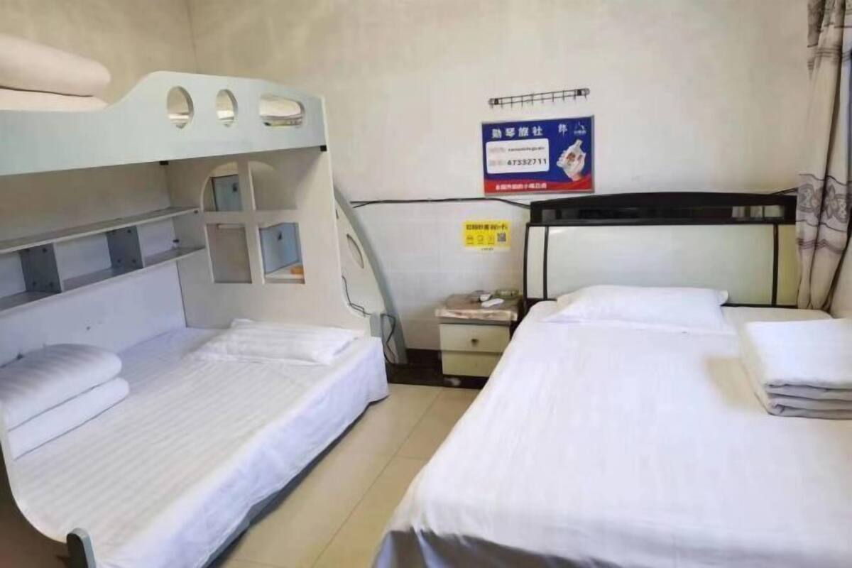 A hotel room with bunk beds, a bedside table, a nightstand, and a poster on the wall.