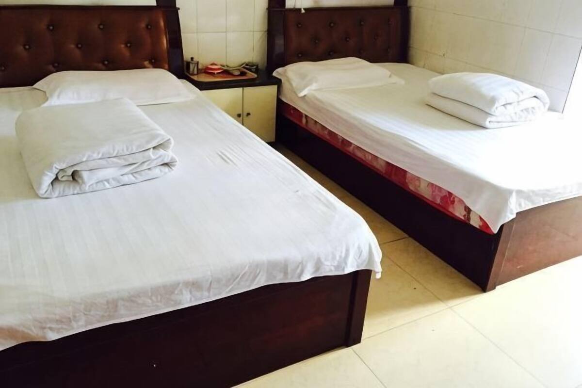 A hotel room with two beds, each with a wooden headboard and white bedding.