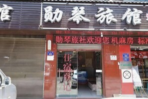 A hotel entrance with a closed shutter, a signboard with Chinese characters, and a visible door. - Chongqing Xunqin Hotel (Chongqing)