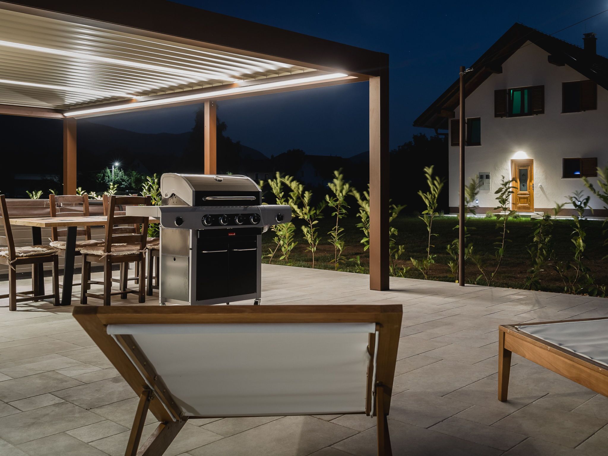 An outdoor patio with a grill, dining table, and chairs.