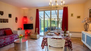 A dining area with a table set for four, a television, and a sofa in the living area. - La Bruyère by Interhome (La Bernerie-en Retz)
