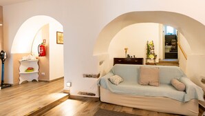 A living room with a light blue sofa, a small white side table, and a wooden floor. There is a staircase leading to an upper level. - Al Forte by Interhome (Arnasco)