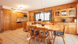 A wooden-paneled kitchen with a round dining table and chairs, a microwave, and a cabinet with a 'PRIVE' sign. - Grand Vue 01-02 by Interhome (Thyon-Les Collons)