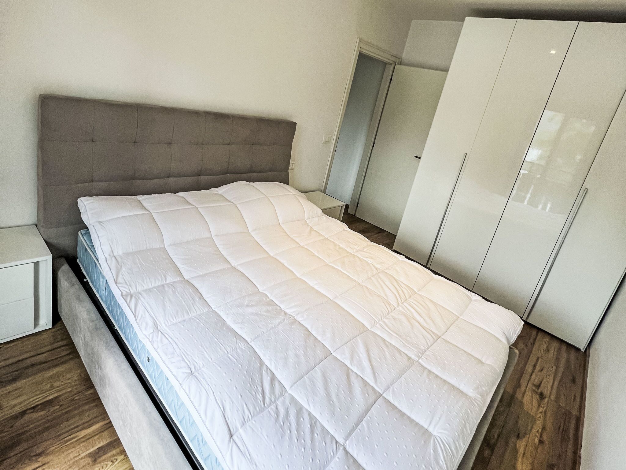 A modern bedroom with a bed, a nightstand, and a wardrobe.