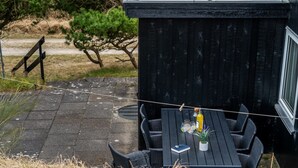 A patio with a black wooden table and chairs, a small potted plant, and a bottle of drink.