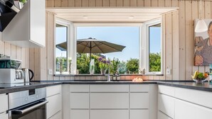 Eine moderne Küche mit weißen Schränken, einem eingebauten Ofen und einem Fenster mit Sonnenschirm.