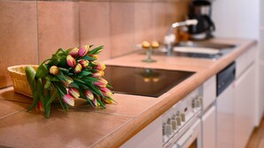 A kitchen with a bouquet of tulips on the counter, a coffee maker, and a toaster. - Ruga Vacation Rental 3 in Ascona (Ascona)
