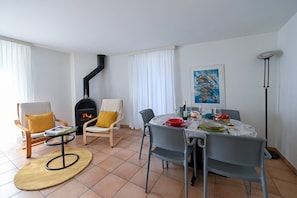 Ein Wohnzimmer mit Kamin, Esstisch, Stühlen und einer Stehlampe.