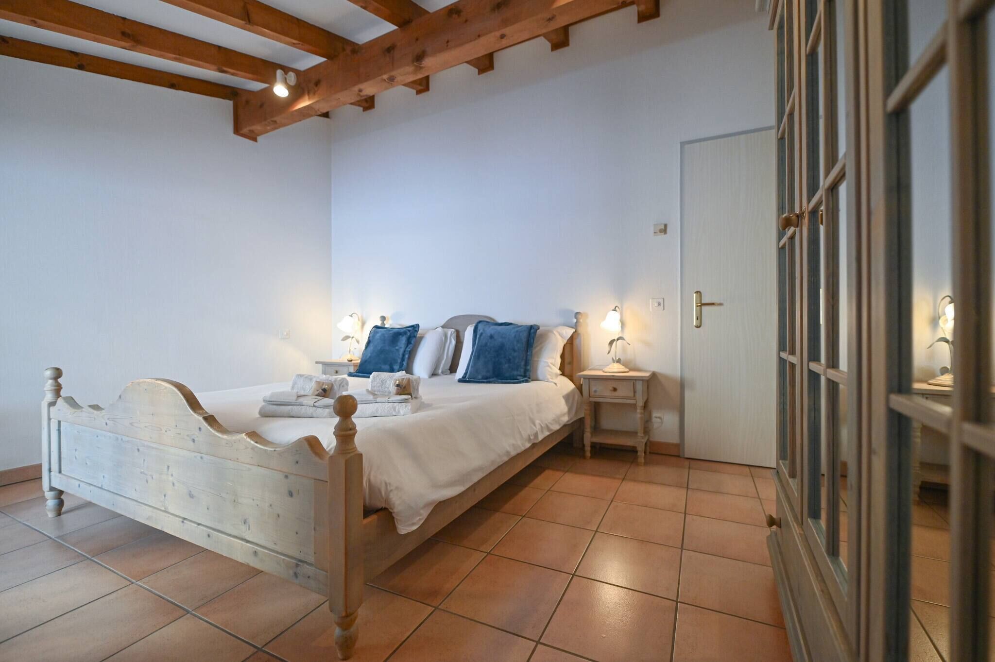 A bedroom with a wooden bed, white bedding, and two bedside tables with lamps.
