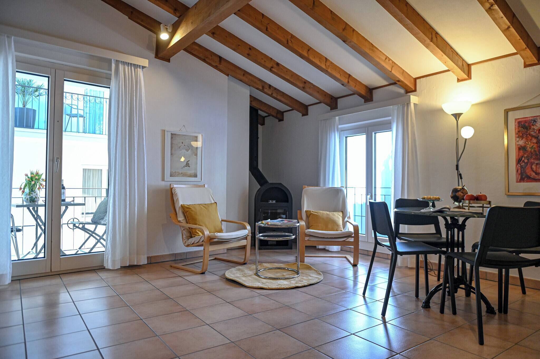 A spacious living area with a fireplace, wooden beams, and a dining table with chairs.