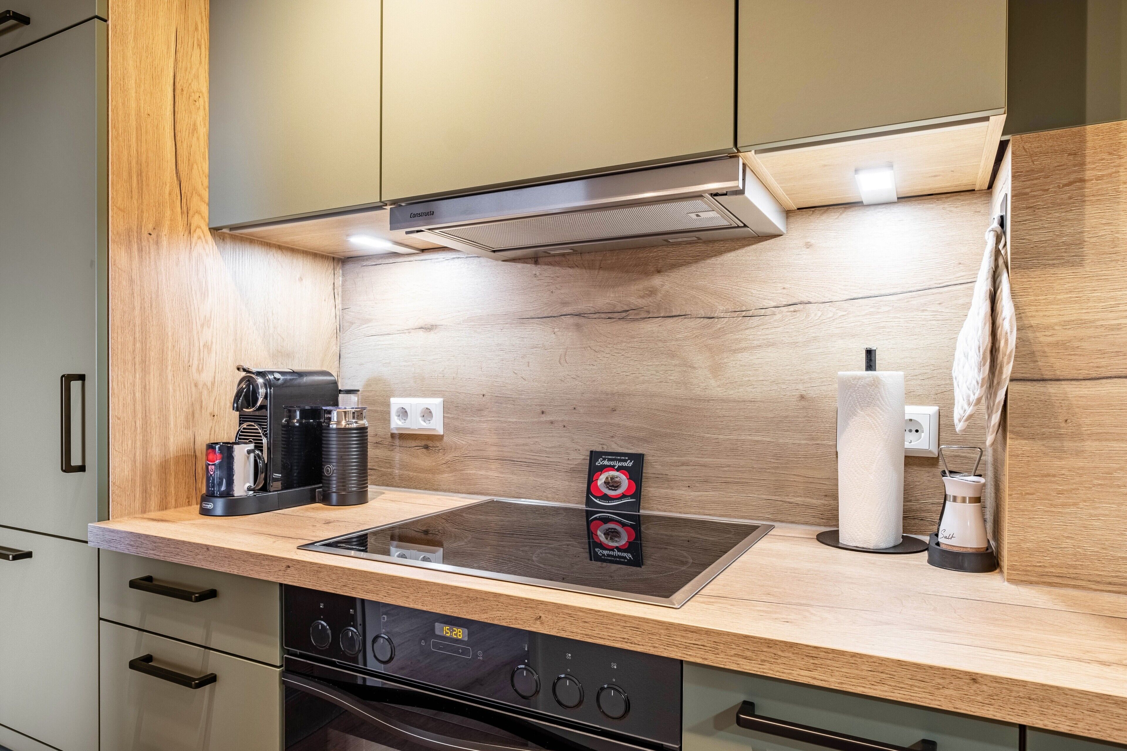 A modern kitchen with a built-in stove, oven, and a coffee maker on the counter.