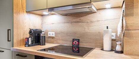 A modern kitchen with a built-in stove, oven, and a coffee maker on the counter.