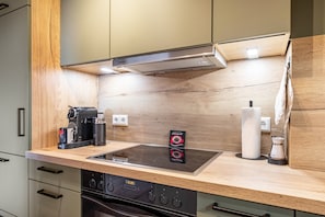 Ett modernt kök med en inbyggd spis, ugn och en kaffebryggare på bänkskivan.