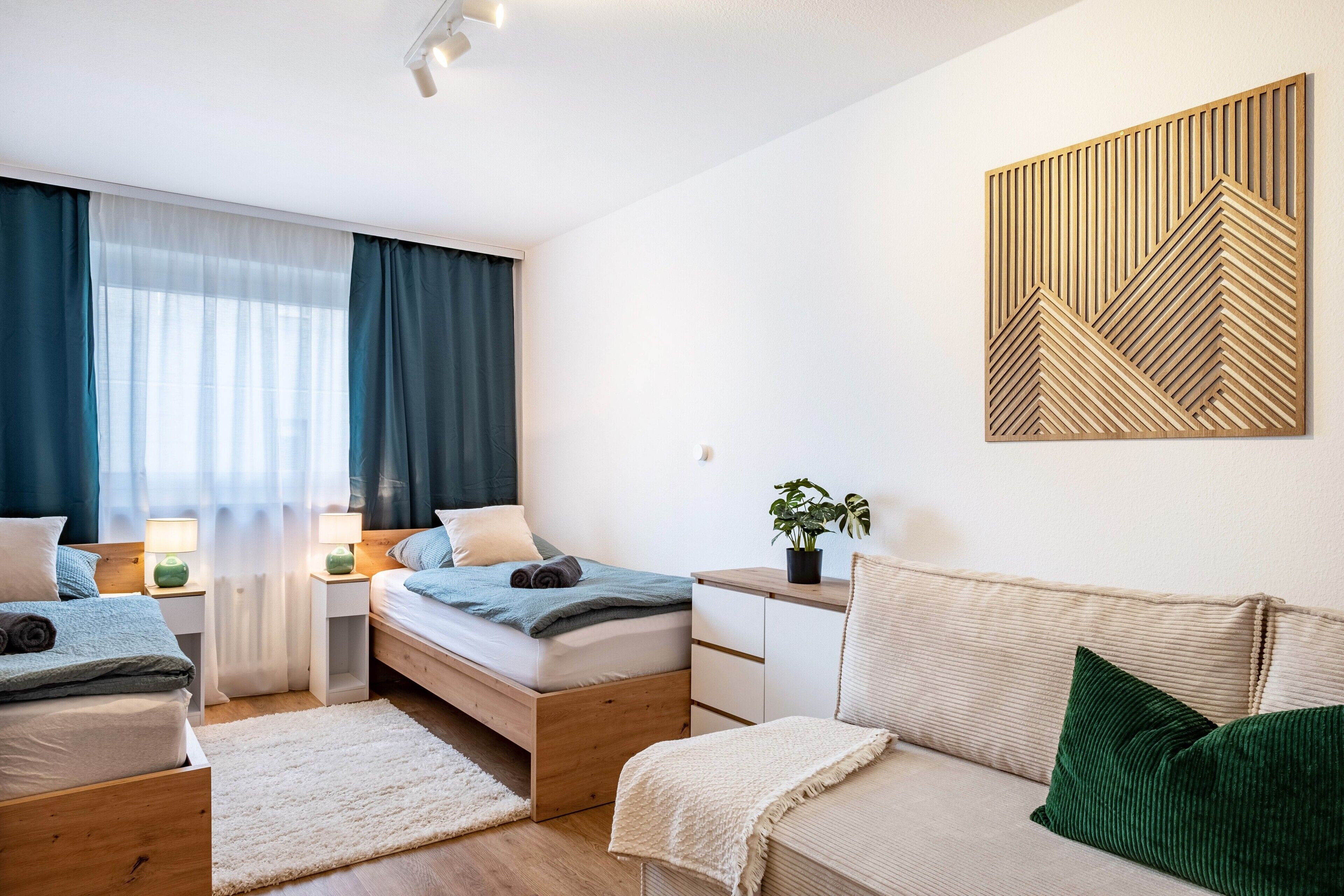 Ein modernes Schlafzimmer mit Bett, Nachttischen, einer Couch und einer Wanddekoration.