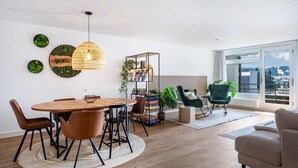 Ein moderner Wohnraum mit Essbereich, einer Bücherwand und Blick auf die Stadt.