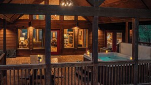 Una cabaña de madera con hidromasaje, comedor y sala de estar acogedora.