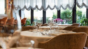 Un ambient de restaurant amb taules rodones, cadira i vasos de vi buits.