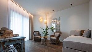 Una sala de estar moderna con un sofá, dos sillones, una mesita de centro y un espejo decorativo.