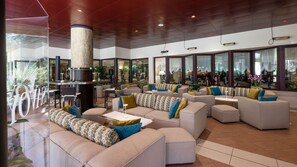 A spacious lounge area with multiple seating options, including sofas and chairs, arranged around a central column.