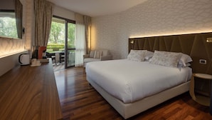 Ein modernes Hotelzimmer mit einem großen Bett, einem Sofa, einem Couchtisch und einem Balkon mit Sitzmöbeln.