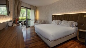 Une chambre d’hôtel moderne dotée d’un grand lit, d’un canapé, d’une table basse et d’un balcon aménagé avec du mobilier d’extérieur.