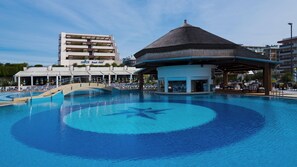 Une piscine en forme d’étoile, un cabanon de plage et un bâtiment d’hôtel en arrière-plan.