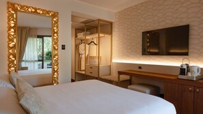 A hotel room with a large bed, a wardrobe, a desk with a coffee machine, and a TV mounted on the wall.