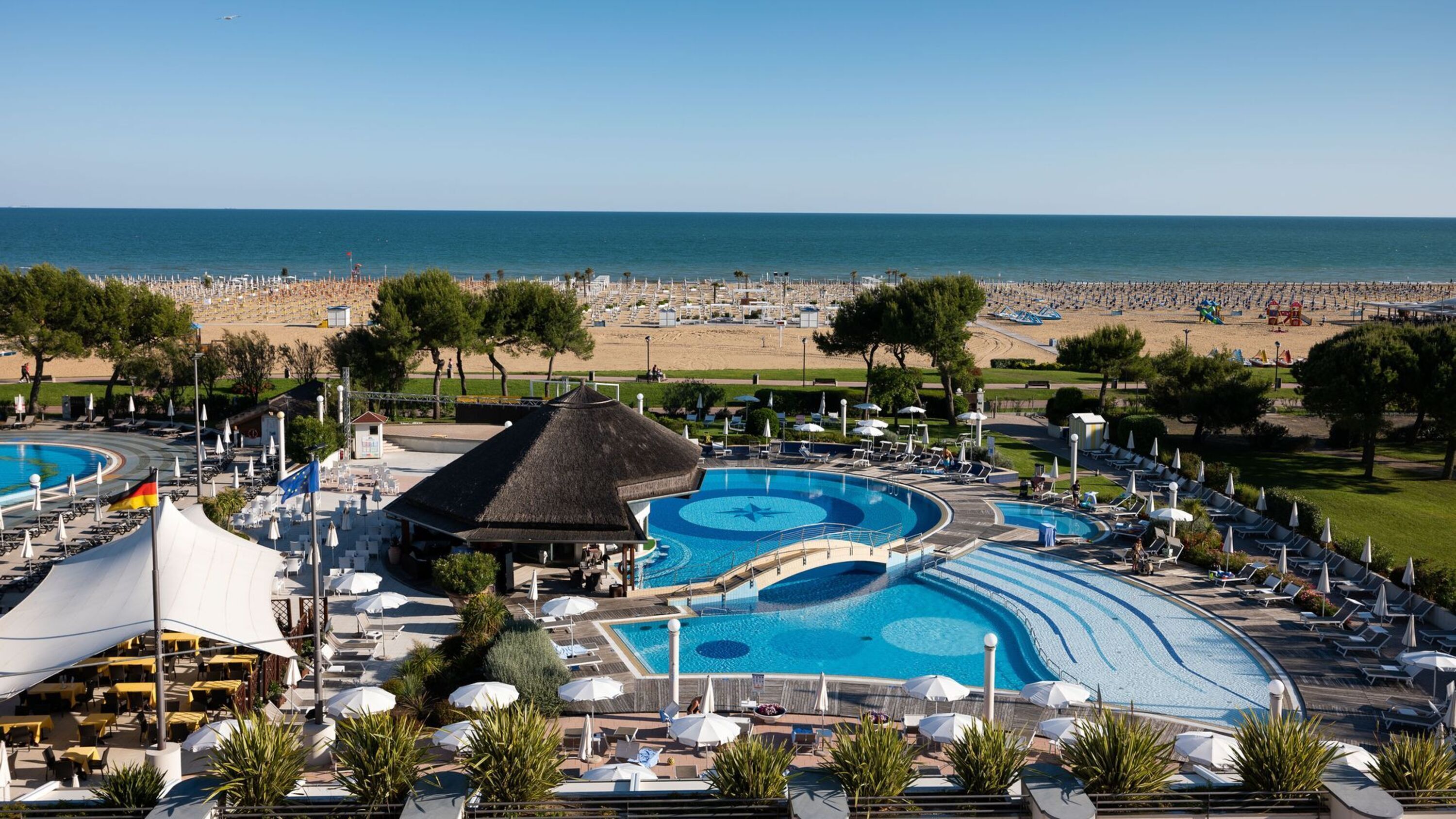 Un complex turístic amb diverses piscines, gandules i vista a la platja.