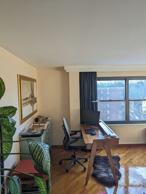 Work in comfort with a desk, chair, and computer monitor, plus a view of the city outside.