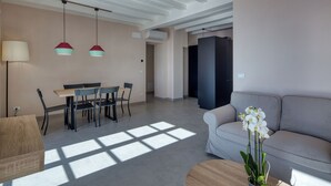 Un salon moderne avec un canapé, une table à manger et des chaises, des luminaires suspendus et une orchidée en pot.