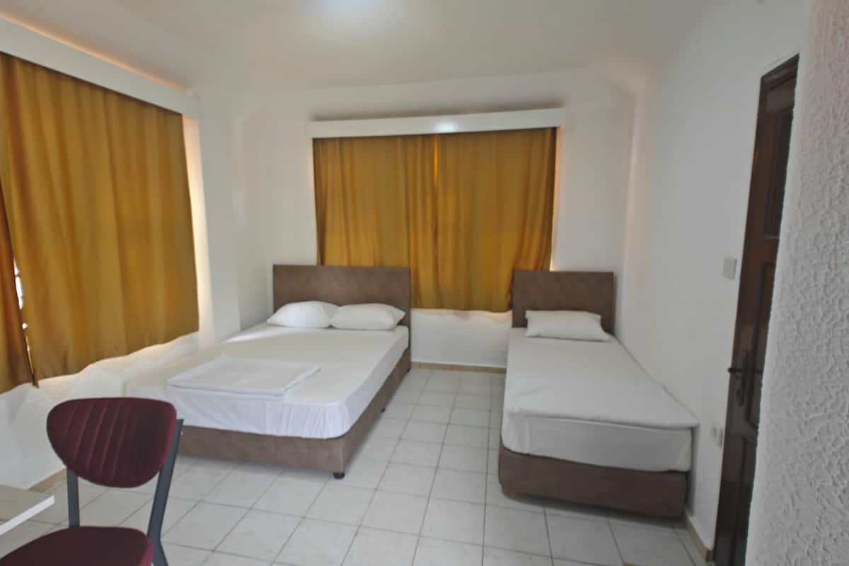 Ein Hotelzimmer mit zwei Einzelbetten, einem Sessel und einem kleinen Tisch.