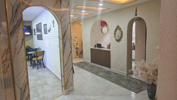 A reception area with a marble floor, a reception desk, and a wall with a Turkish flag and a mirror.