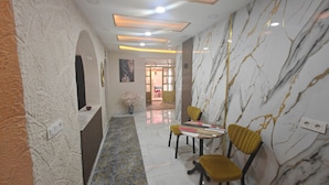 A hallway with marble walls, a patterned floor, and a table with chairs.